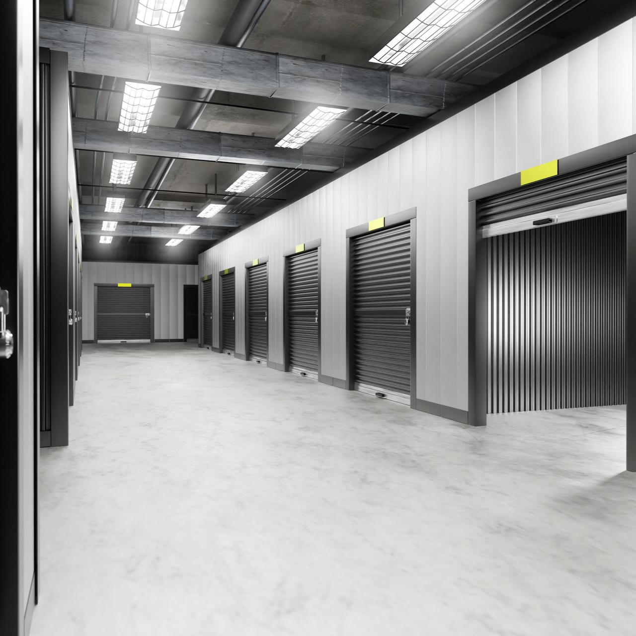 Un couloir lumineux et moderne d'un centre de self-stockage intérieur, avec des rangées de portes sectionnelles métalliques grises.