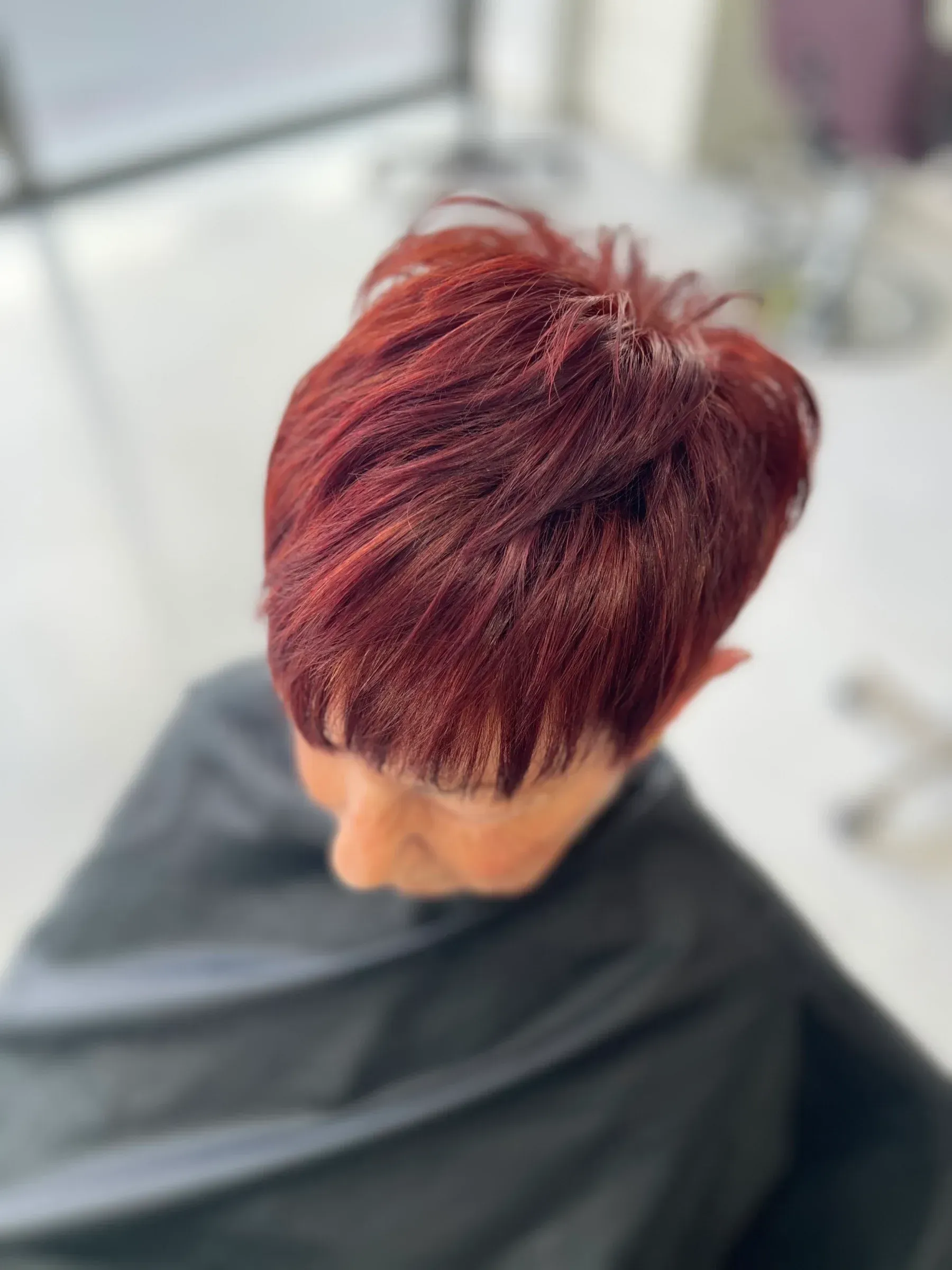 Una mujer con cabello corto y rojo está sentada en una silla.