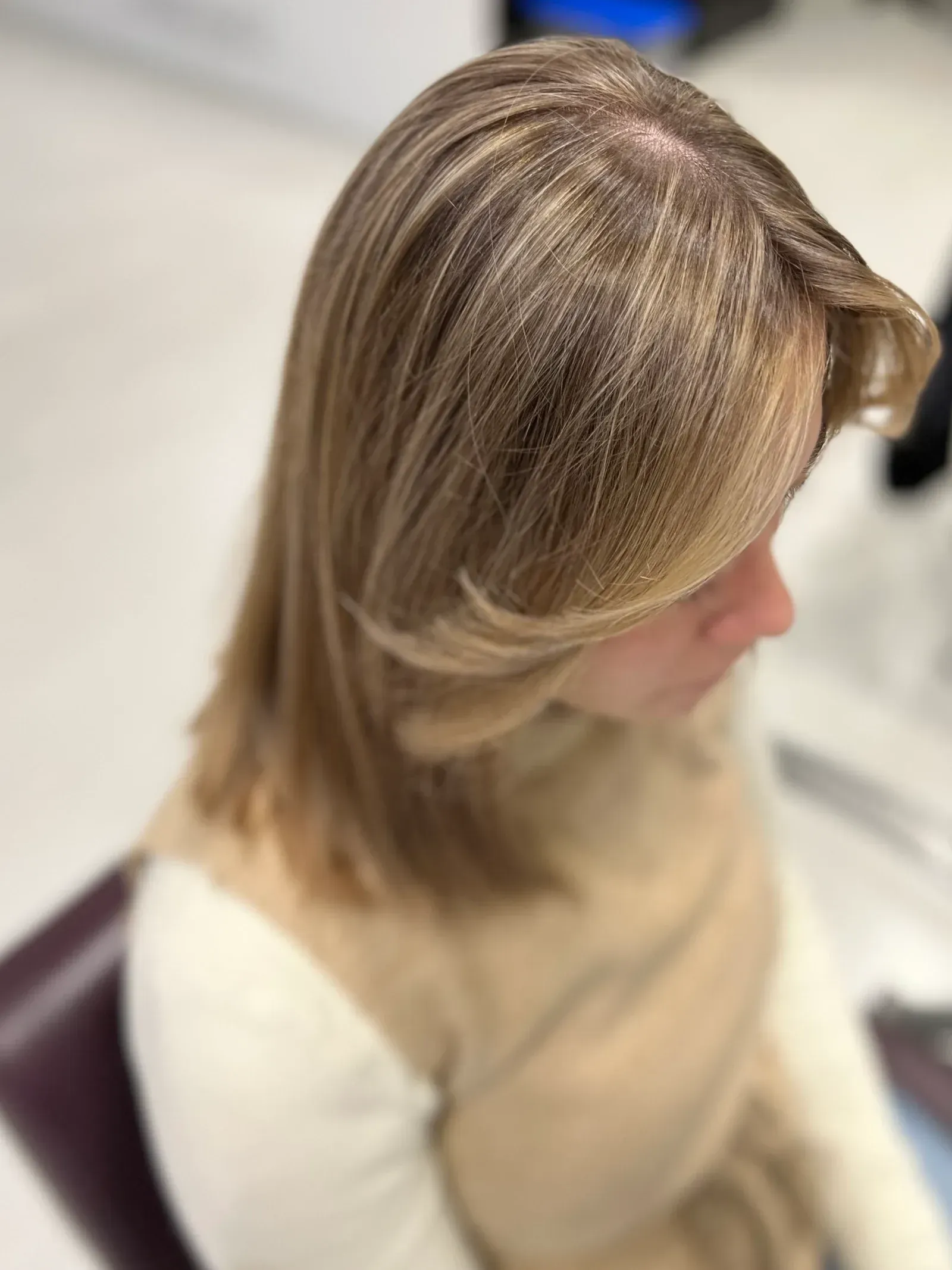 Una mujer con cabello rubio está sentada en una silla.