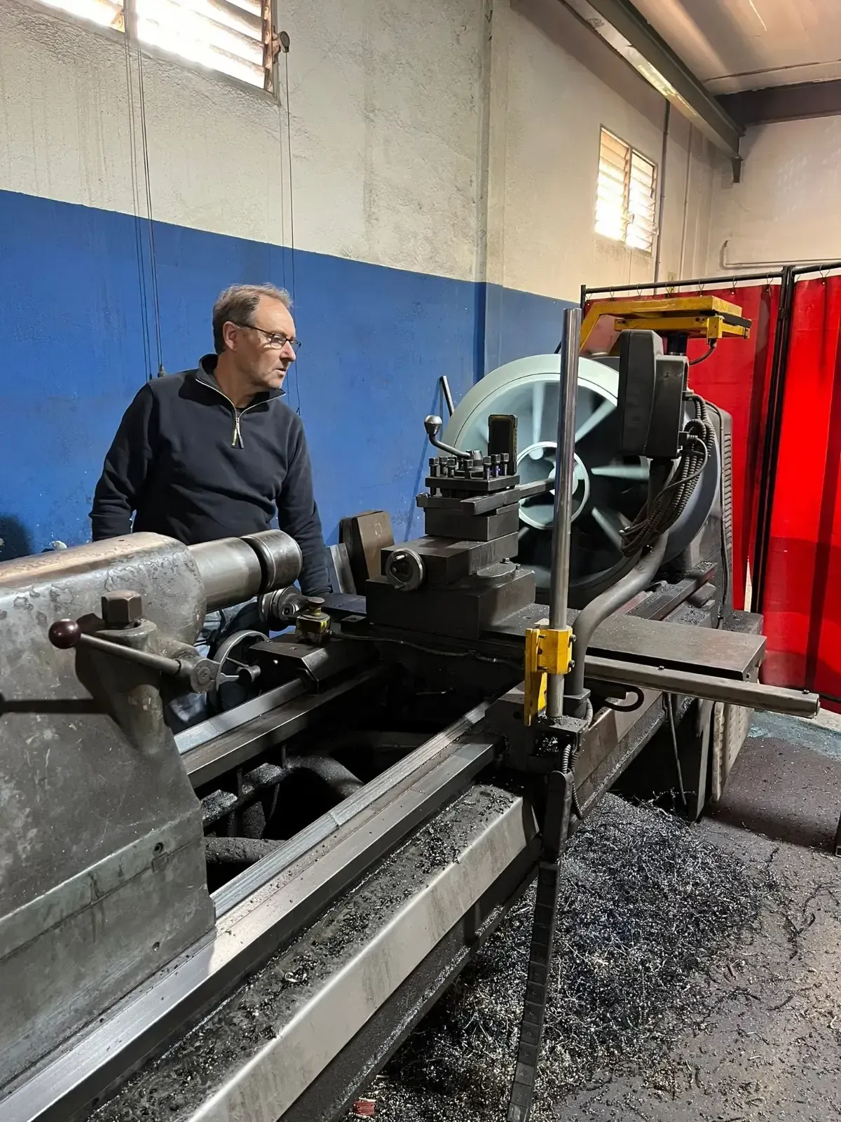 Gran torno CNC industrial con pieza de trabajo metálica y panel de control en un taller de fábrica.