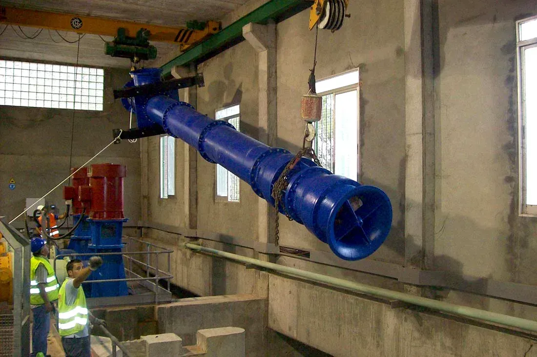 Conductos industriales azules instalados en una habitación de hormigón con trabajadores cerca.