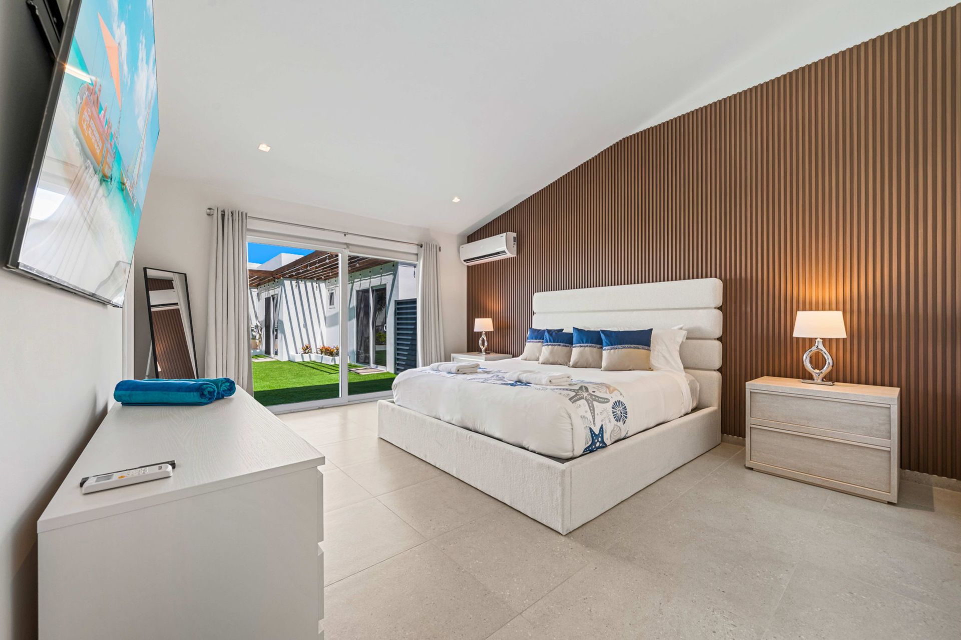 Bright modern bedroom with a bed, nightstands, wall art, and sliding doors to a small patio.