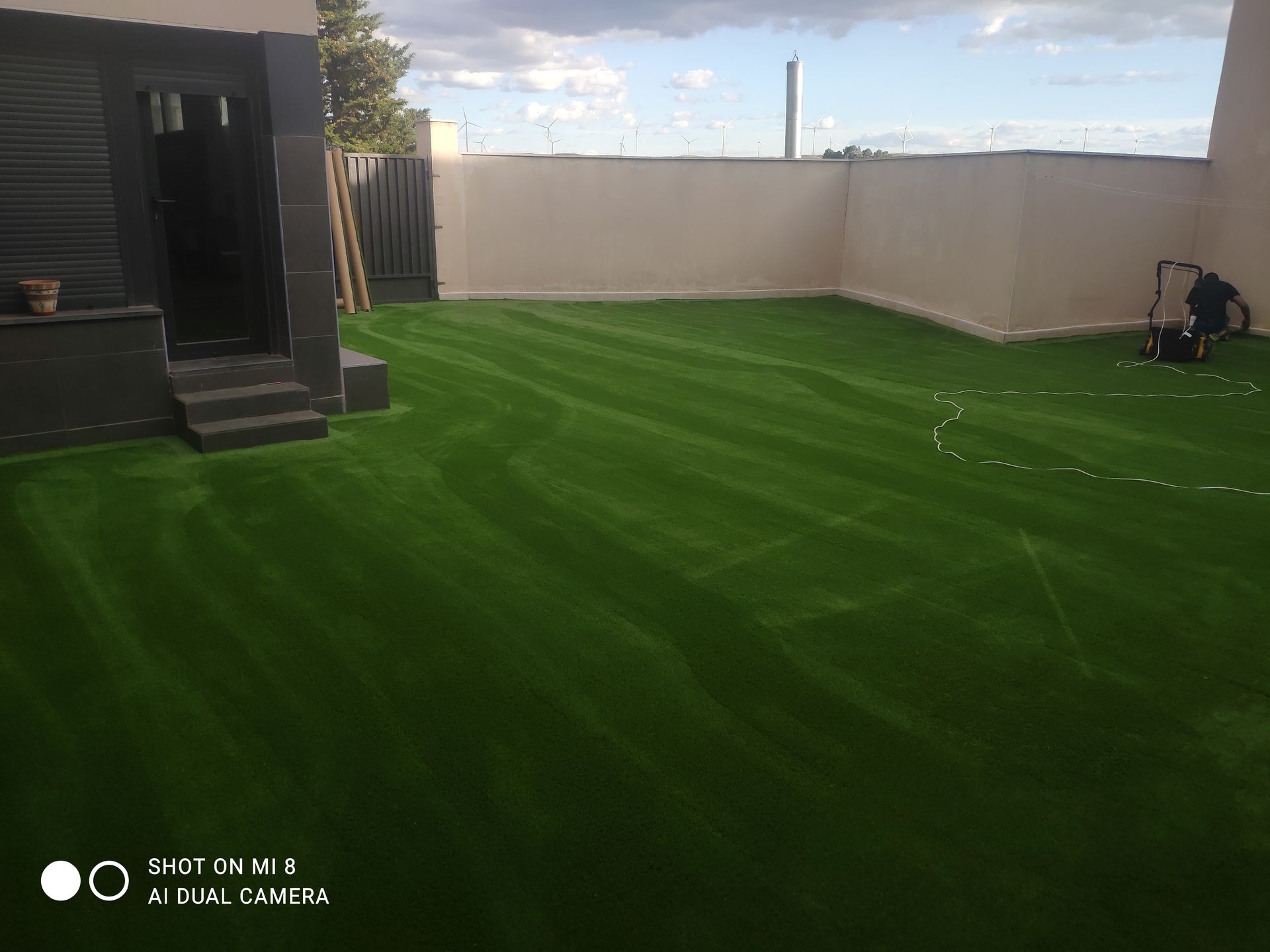 Una cortadora de césped está cortando un césped verde y exuberante en un patio trasero.