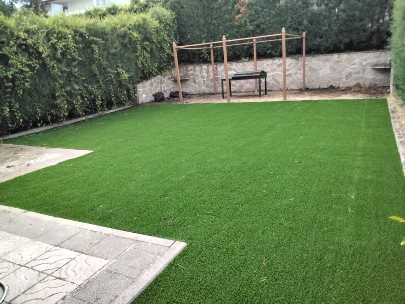 Un patio trasero con un exuberante césped verde y un banco.