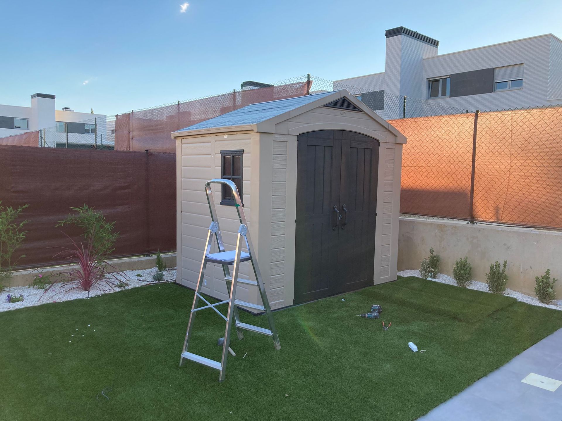 Un cobertizo con una escalera delante en un patio trasero.