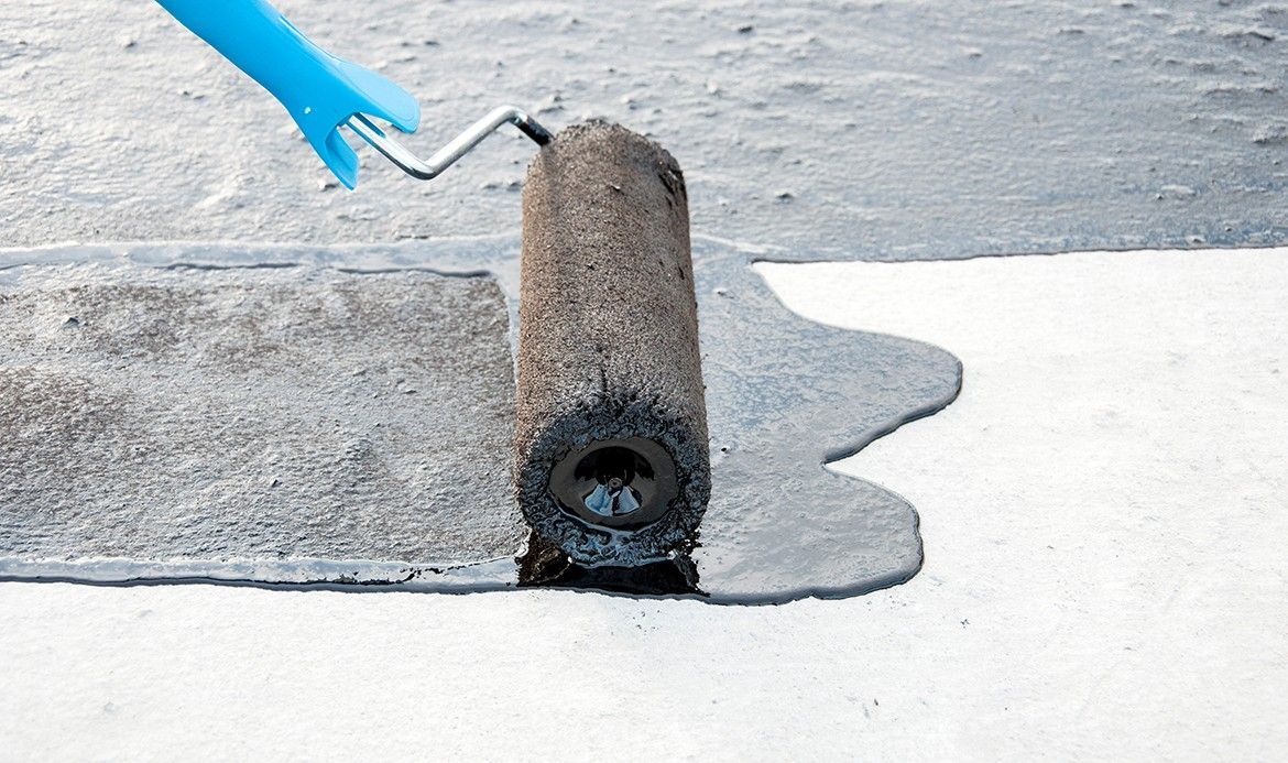 Una persona está usando un rodillo de pintura para pintar una superficie de hormigón.