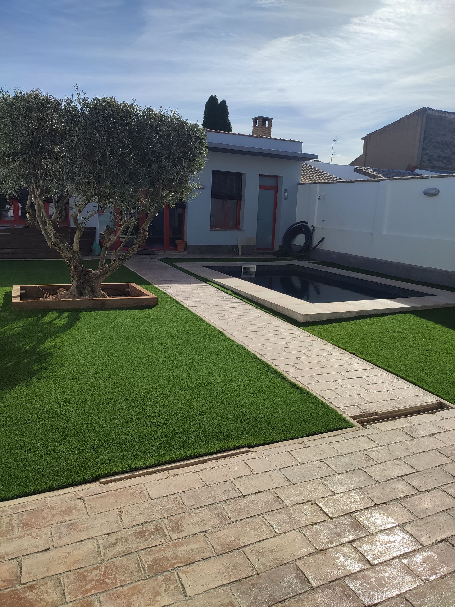 Una pasarela de ladrillos que conduce a una piscina en un patio trasero.