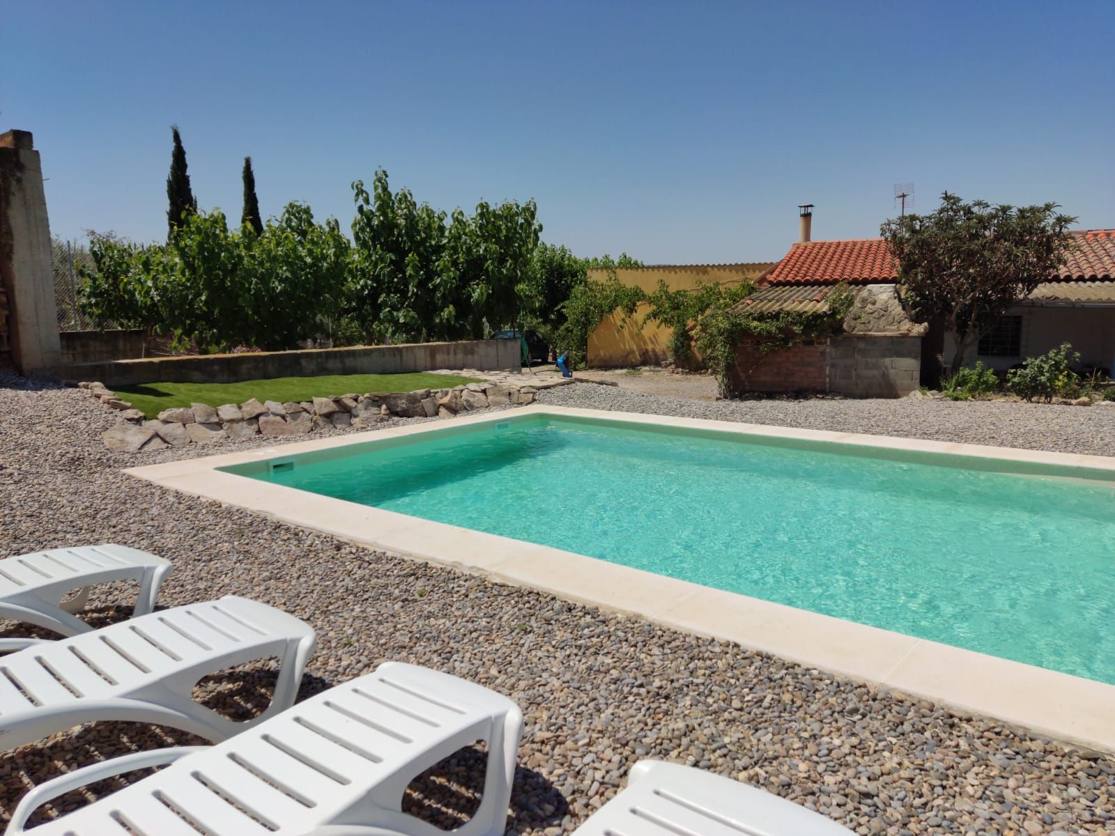 Una gran piscina está rodeada de tumbonas blancas.