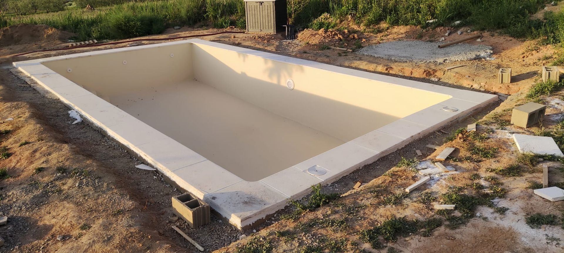 Una gran piscina vacía se encuentra encima de un campo de tierra.