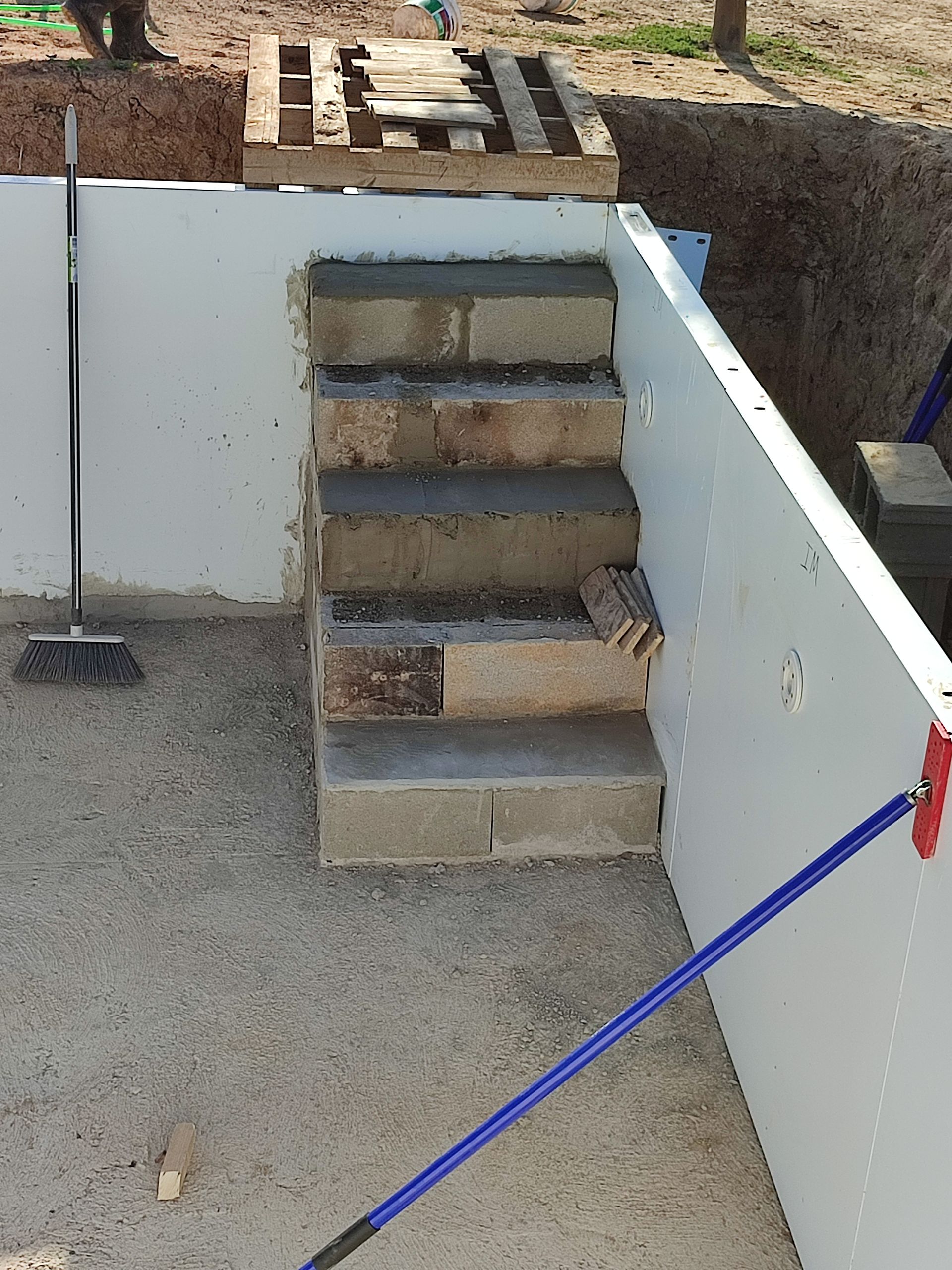 Una escoba azul está sentada junto a un conjunto de escaleras.