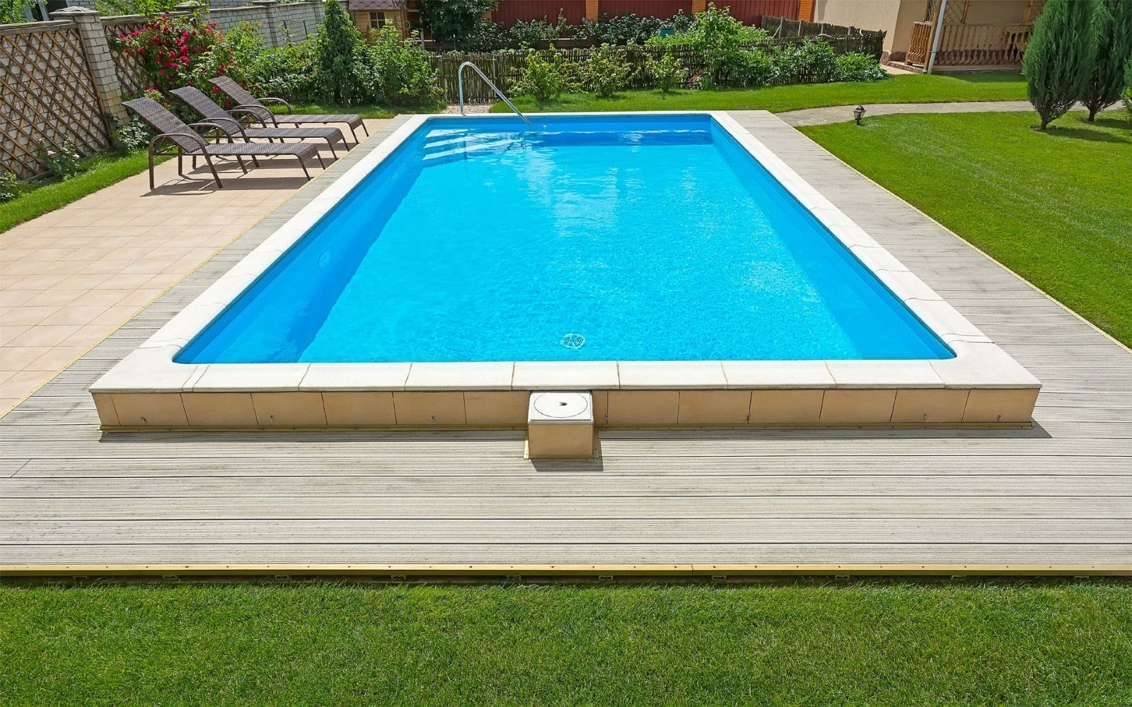 Una gran piscina está rodeada de sillas de jardín y una terraza de madera.