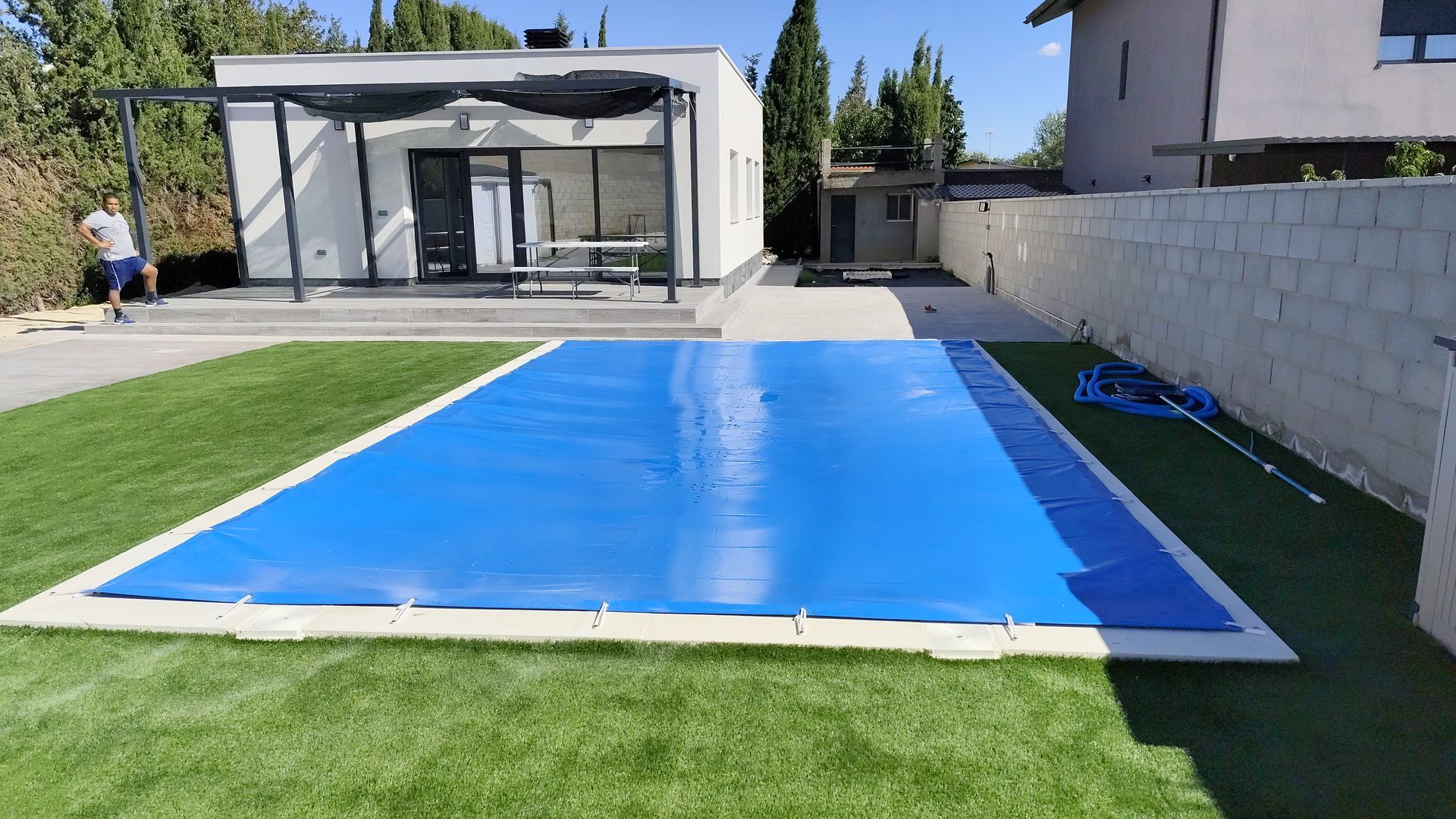 Una lona azul cubre una piscina delante de una casa.