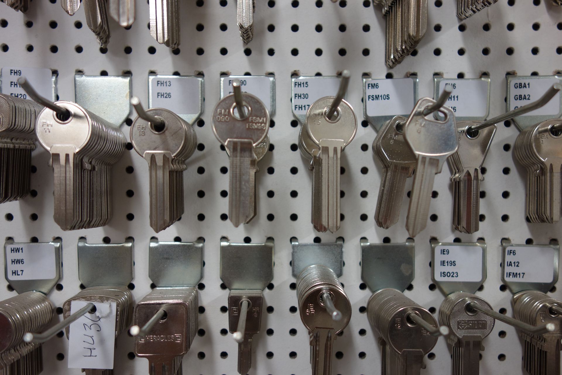 Des clés accrochées à un panneau perforé avec des supports métalliques étiquetés.