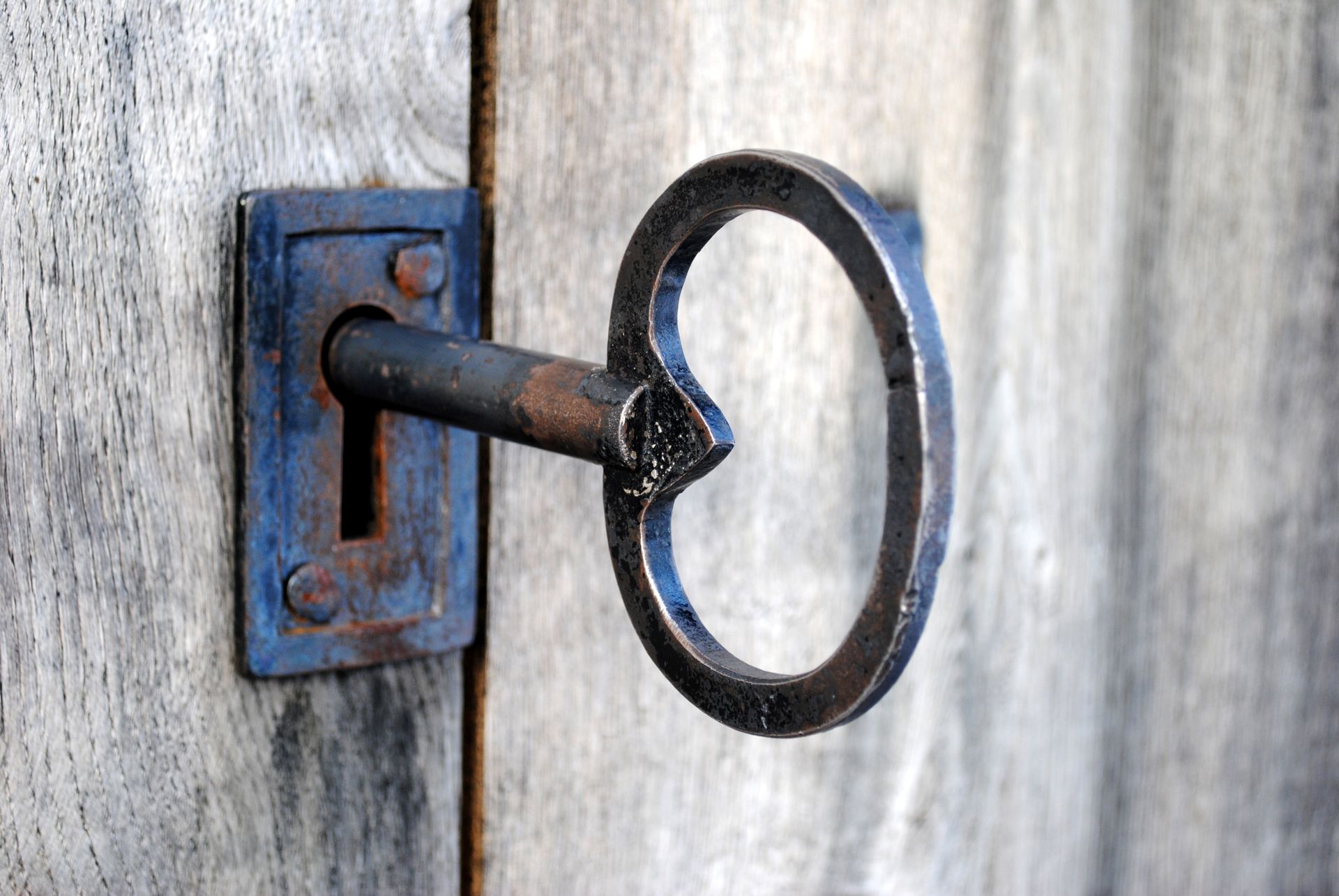 Un forgeron martèle du métal incandescent sur une enclume en plein air, portant un tablier et des gants.