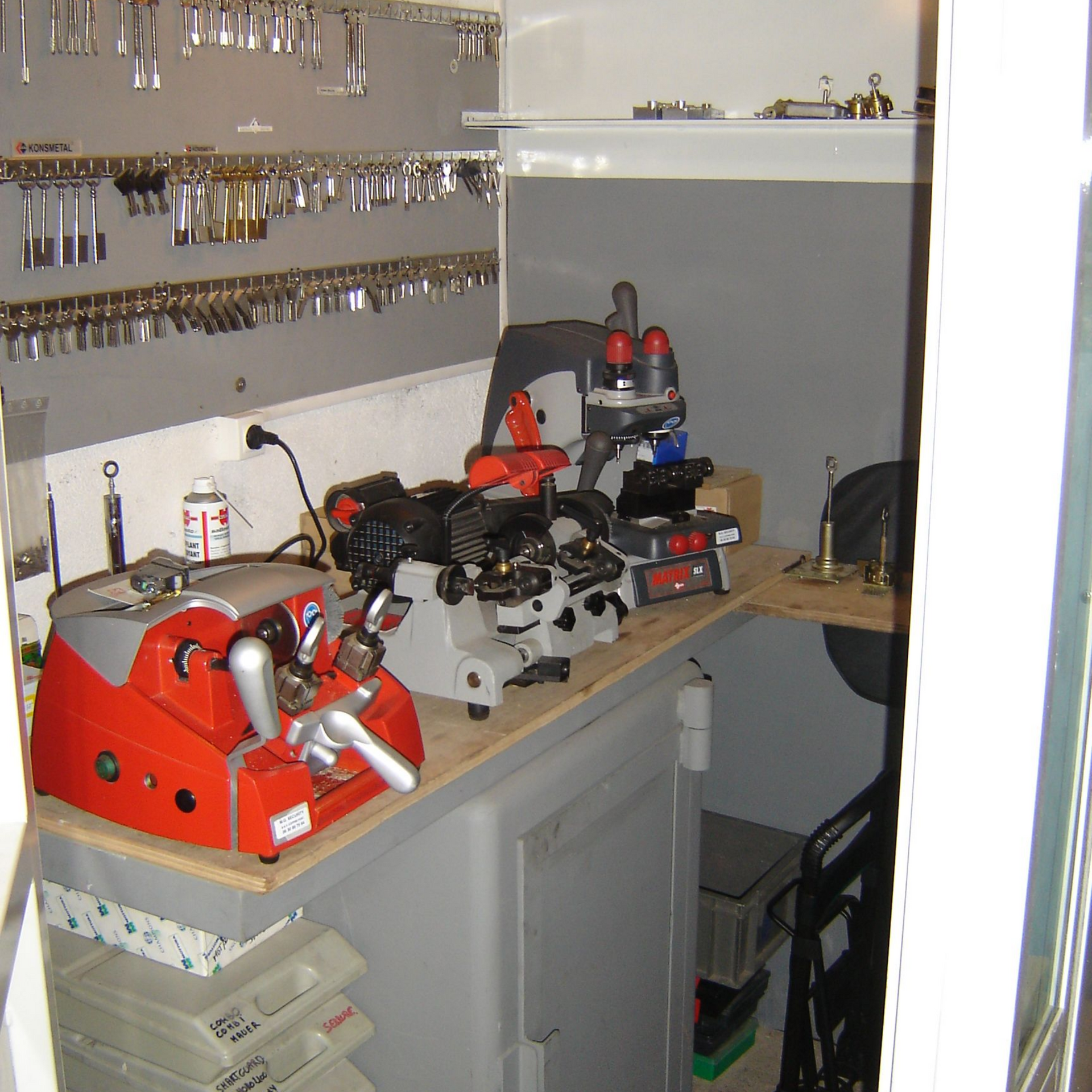 L'atelier d'un serrurier. Des machines à tailler les clés sur un comptoir, des clés accrochées au mur.