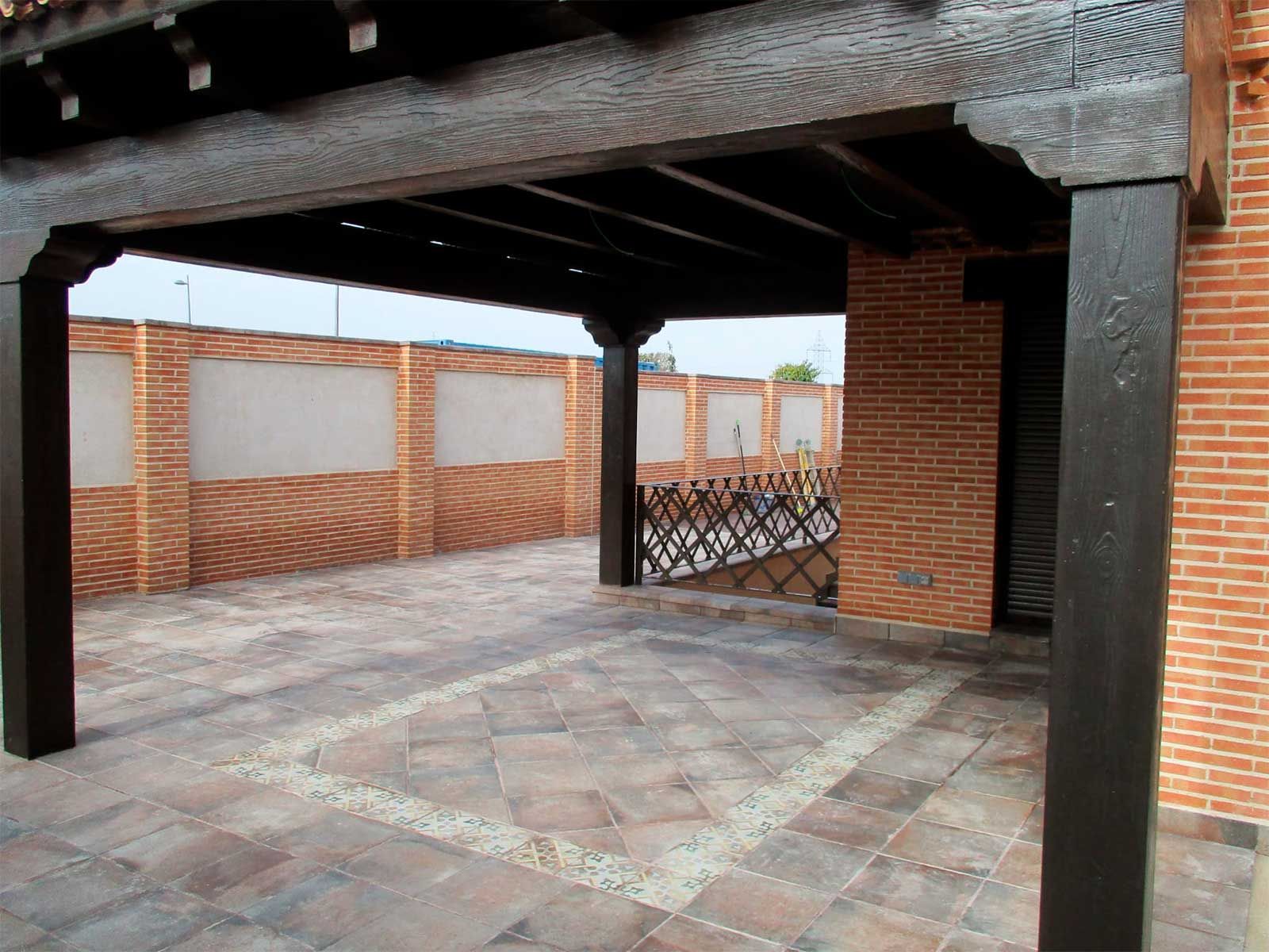 Un edificio de ladrillo con una pérgola de madera delante.