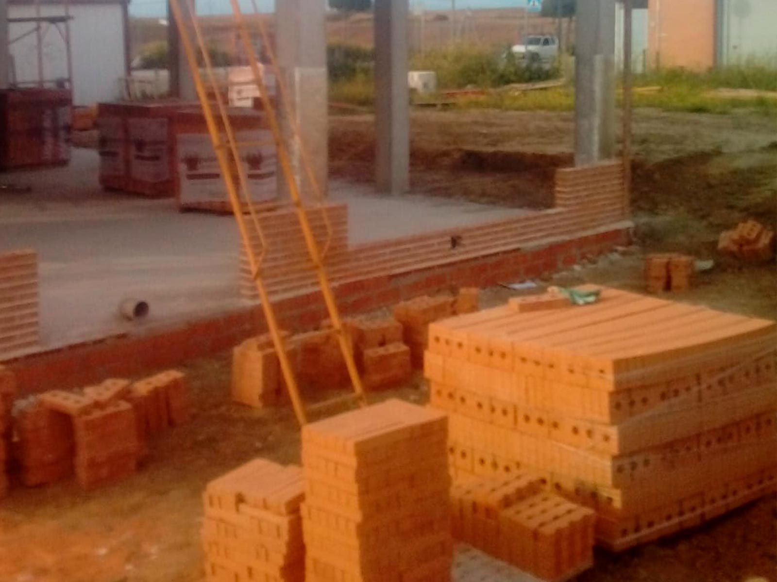 Una pila de ladrillos se encuentra en el suelo frente a un edificio en construcción.