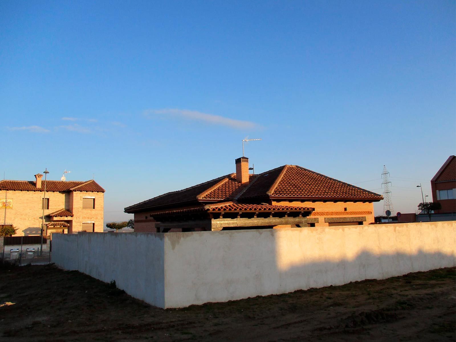 Una casa de ladrillo con una valla blanca delante.