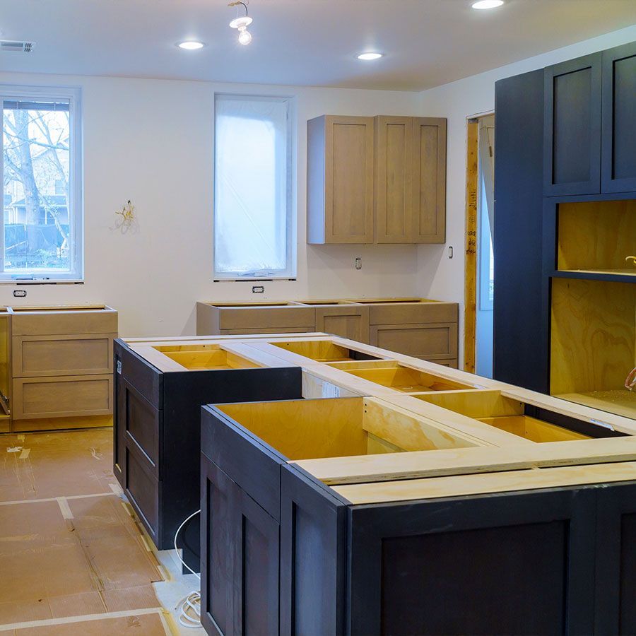 Una cocina en construcción con gabinetes negros y gabinetes de madera.