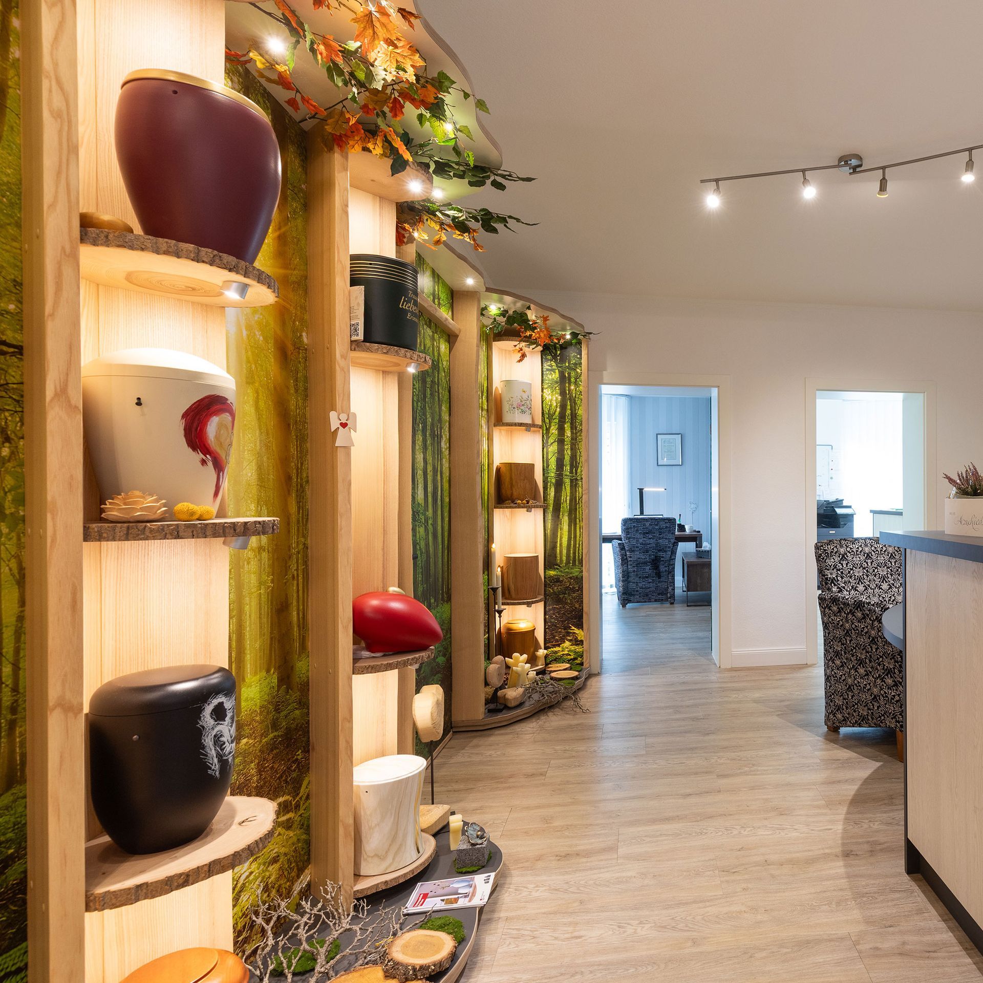 Interieur mit Urnenregalen vor einem Waldmotiv, warmer Beleuchtung und Blick auf einen Flur.