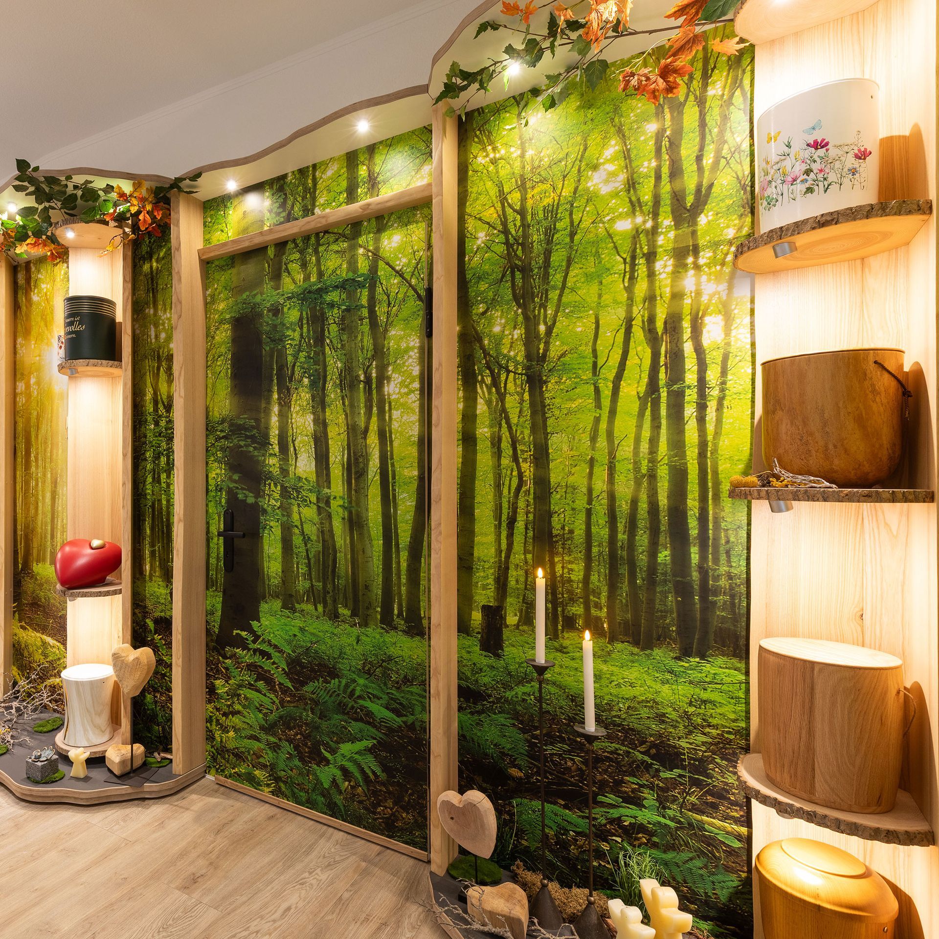 Ausstellungsraum mit Urnen für die Feuerbestattung vor einer Kulisse mit Waldmotiv, Holzregalen und Kerzen.