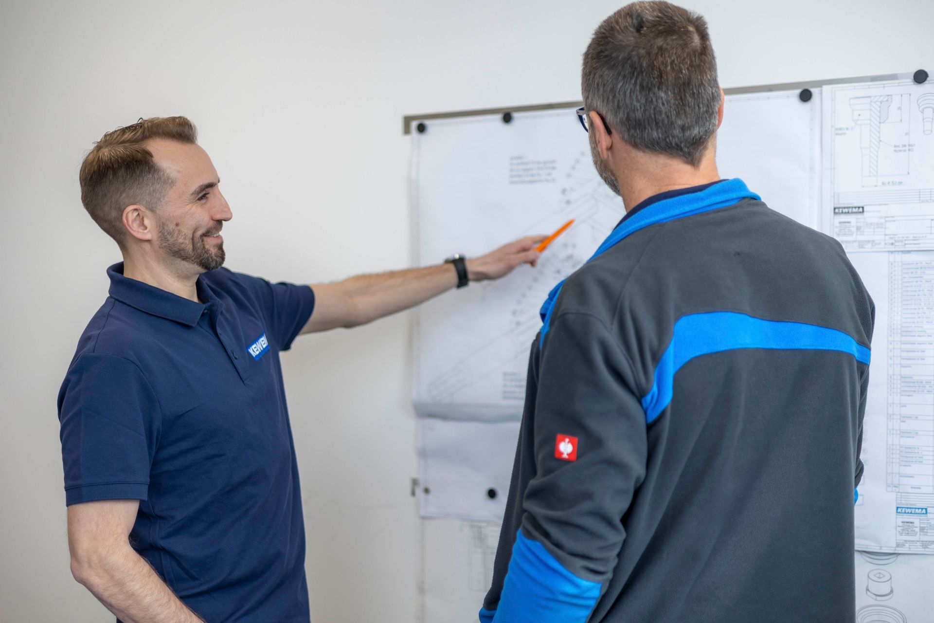 Zwei Männer stehen nebeneinander vor einem Whiteboard.