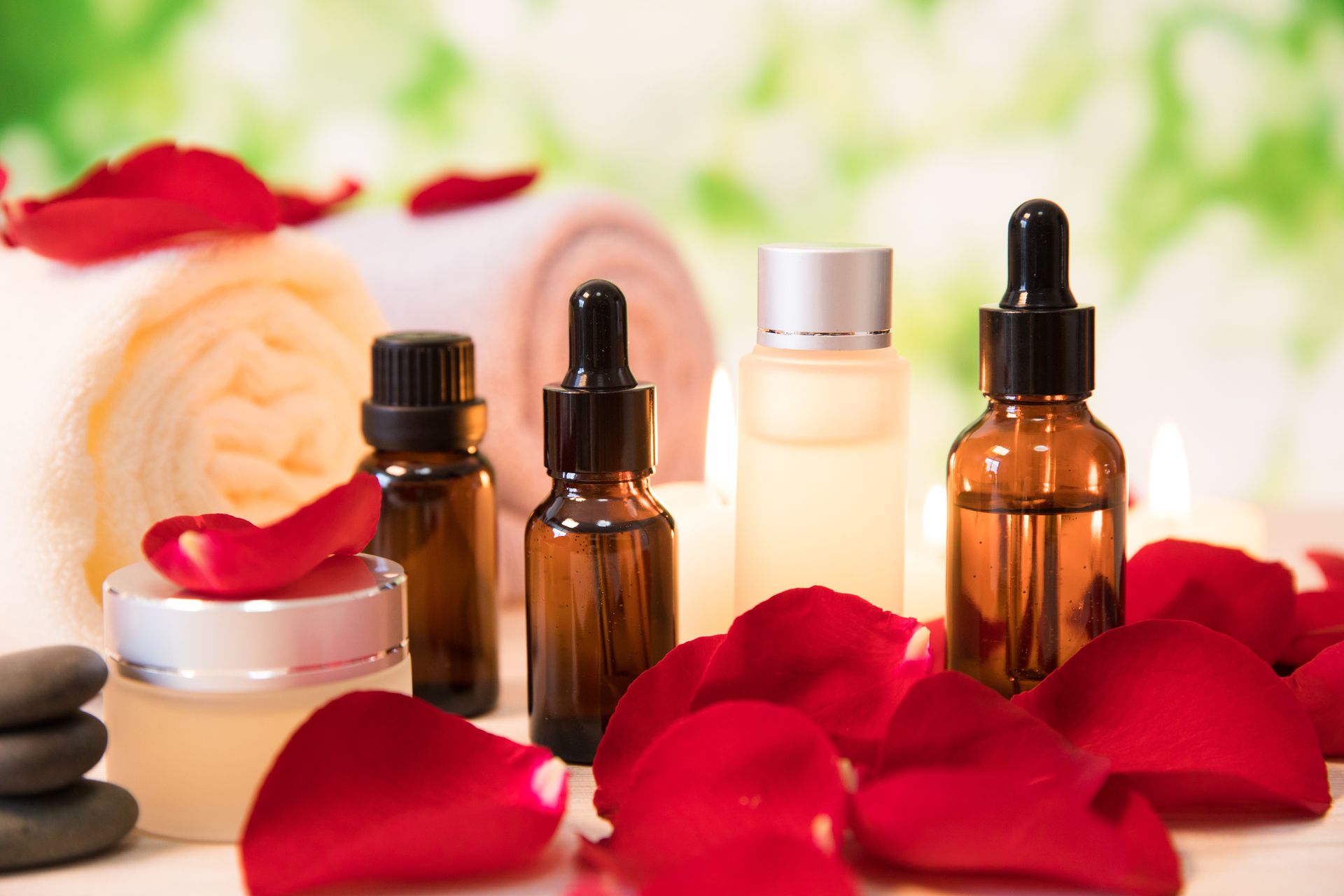 Scena spa: butelki z olejkami, płatki róż, zwinięty ręcznik.