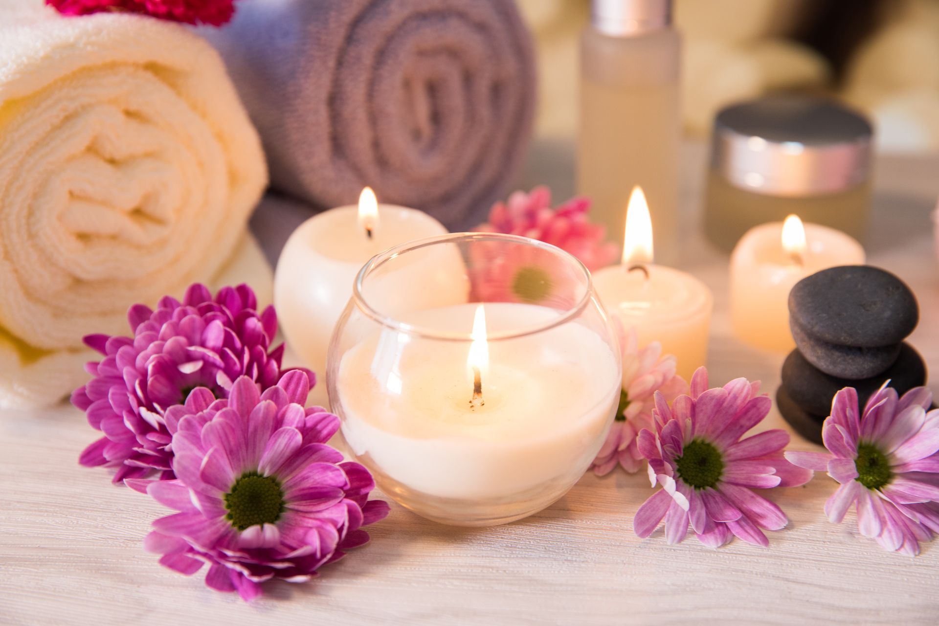 Świece, kwiaty, ręczniki i produkty spa ułożone na stole sprzyjają relaksowi i dobremu samopoczuciu.