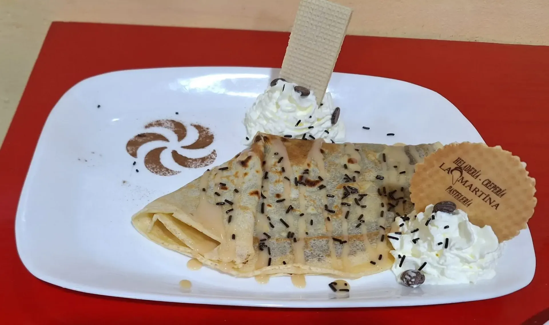 Crepe bañada en chocolate sobre una tabla de madera con fresas, bajo una cálida iluminación de postre.