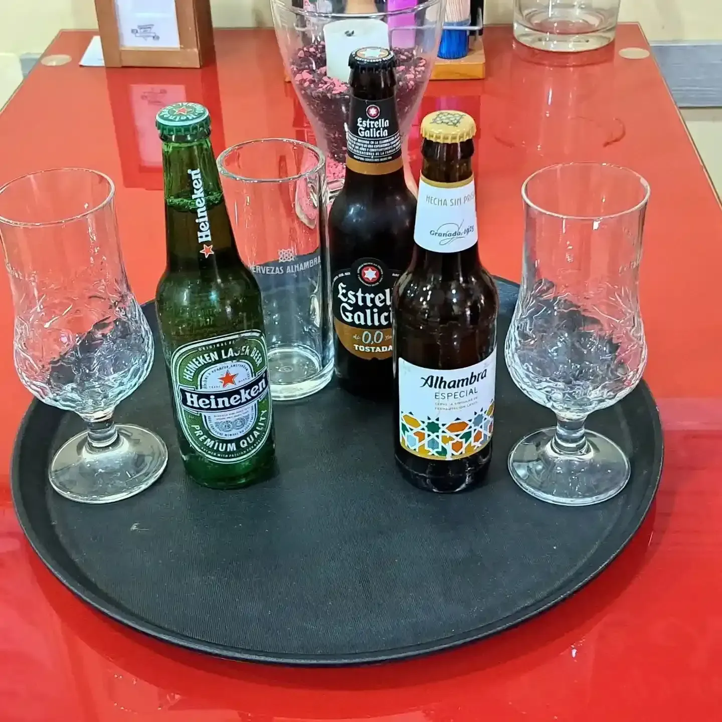 Dos vasos de cerveza helados junto a un plato de alitas de pollo a la parrilla sobre una mesa de madera.