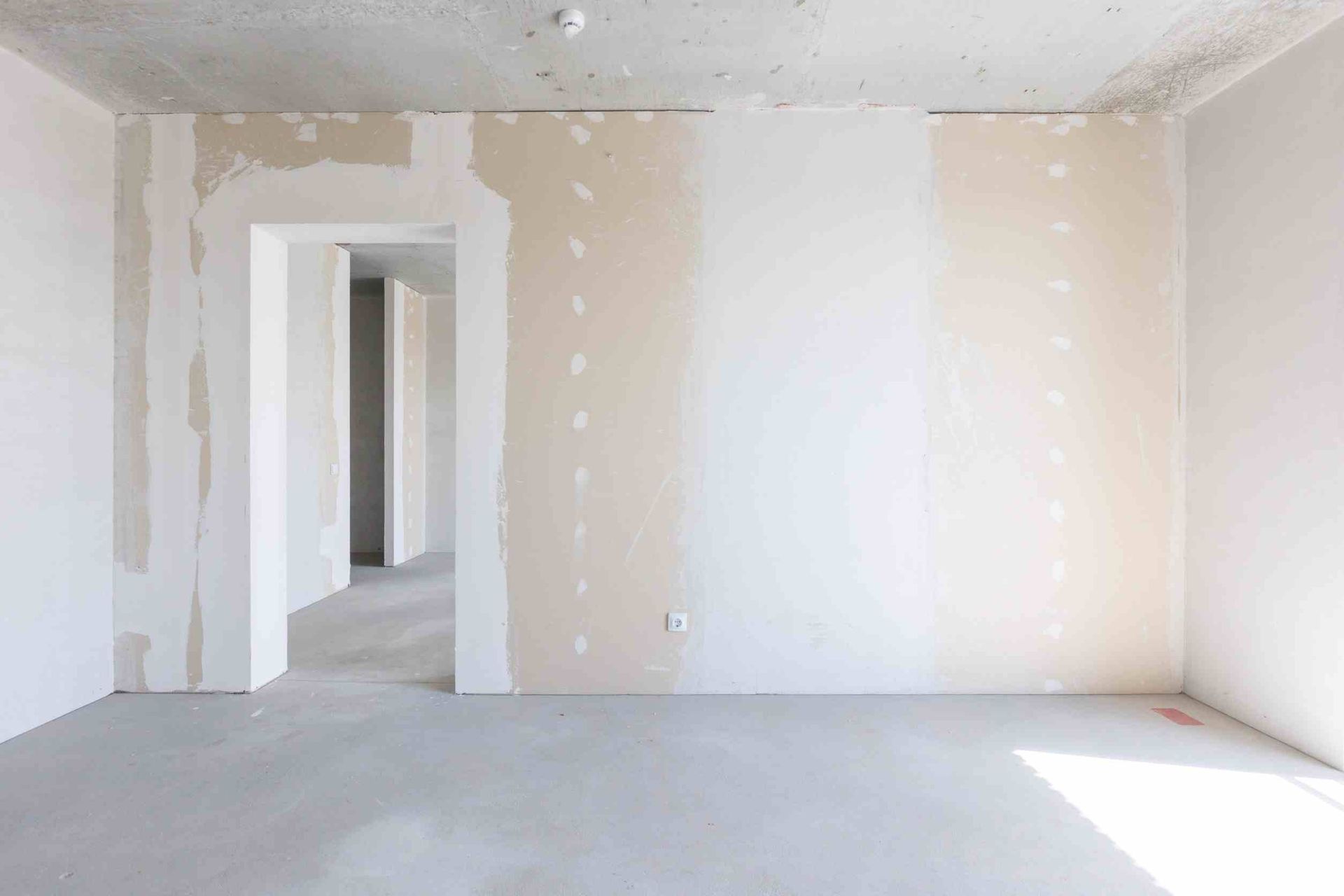 Una habitación vacía con paredes blancas y una puerta que conduce a otra habitación.