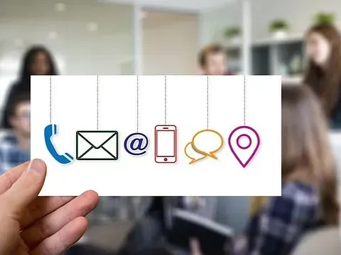 Una persona sostiene una tarjeta con íconos de contacto.