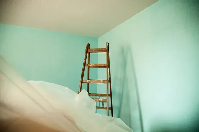 Una escalera de madera está sentada en una habitación con paredes azules.