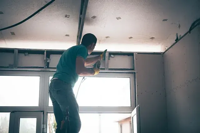 Un hombre está trabajando en el techo de una habitación.