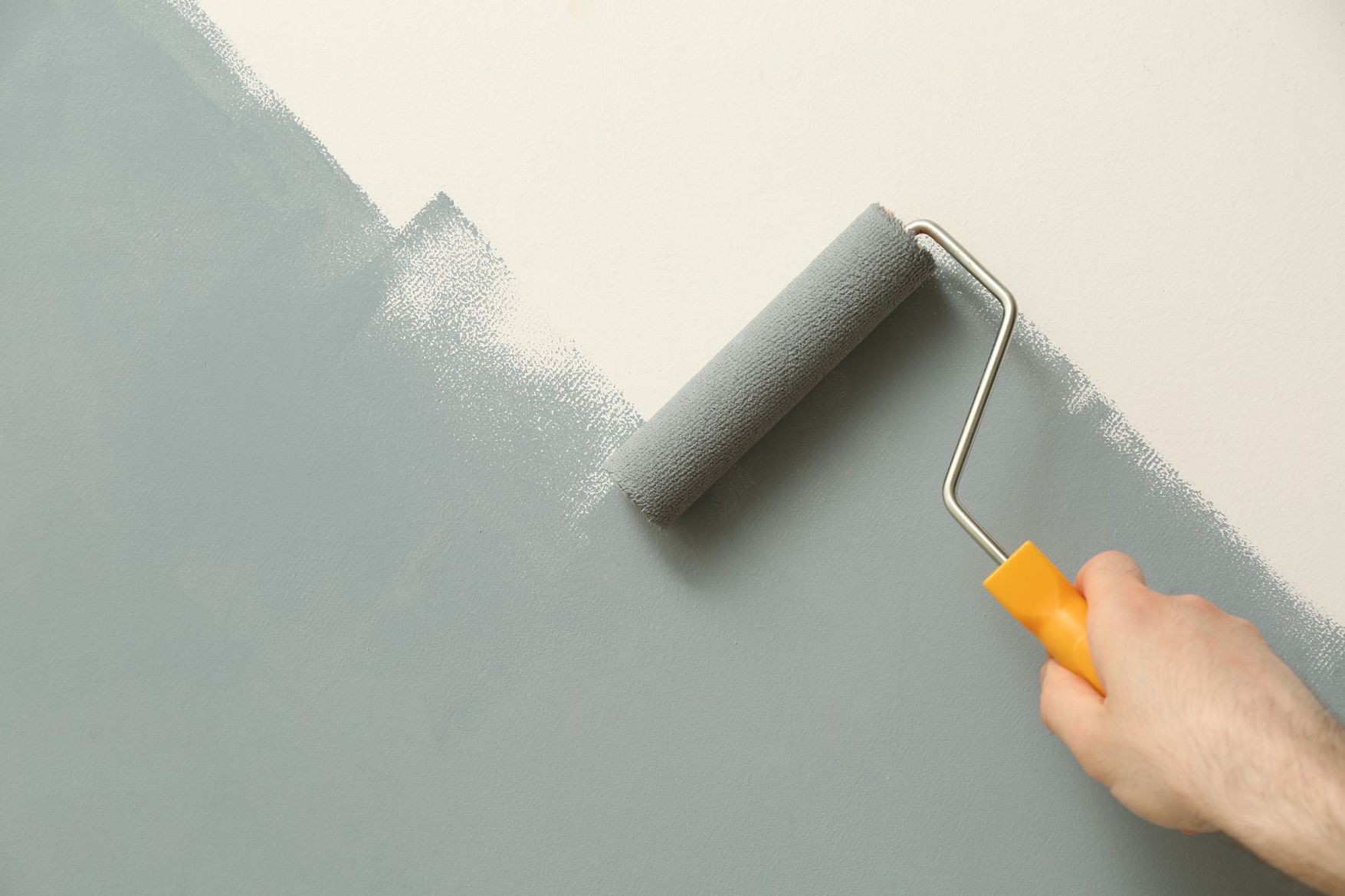 Peindre un mur gris à la main avec un rouleau à peinture
