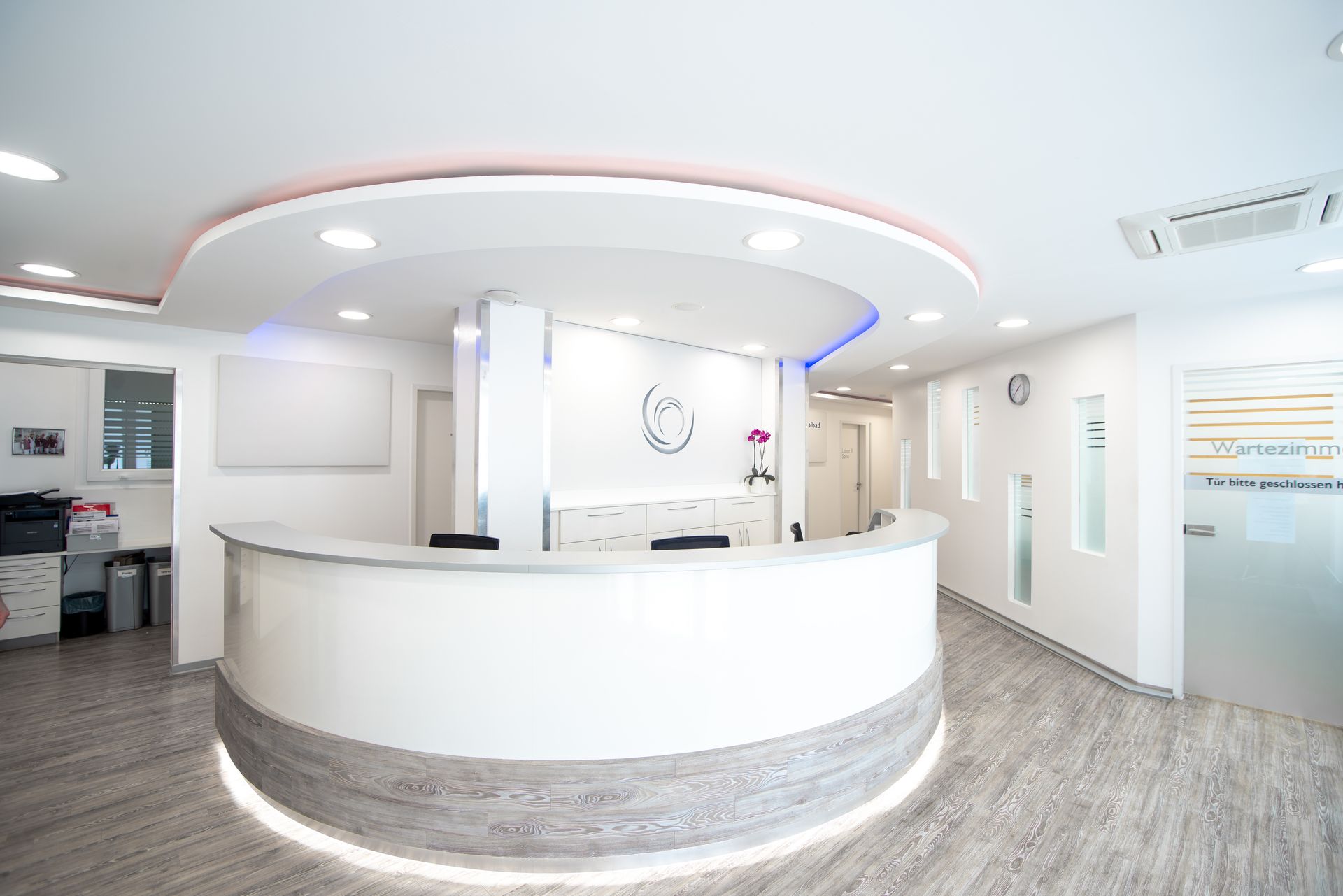 Eine Arztpraxis mit einem Telefon auf dem Schreibtisch und einer Uhr an der Wand.