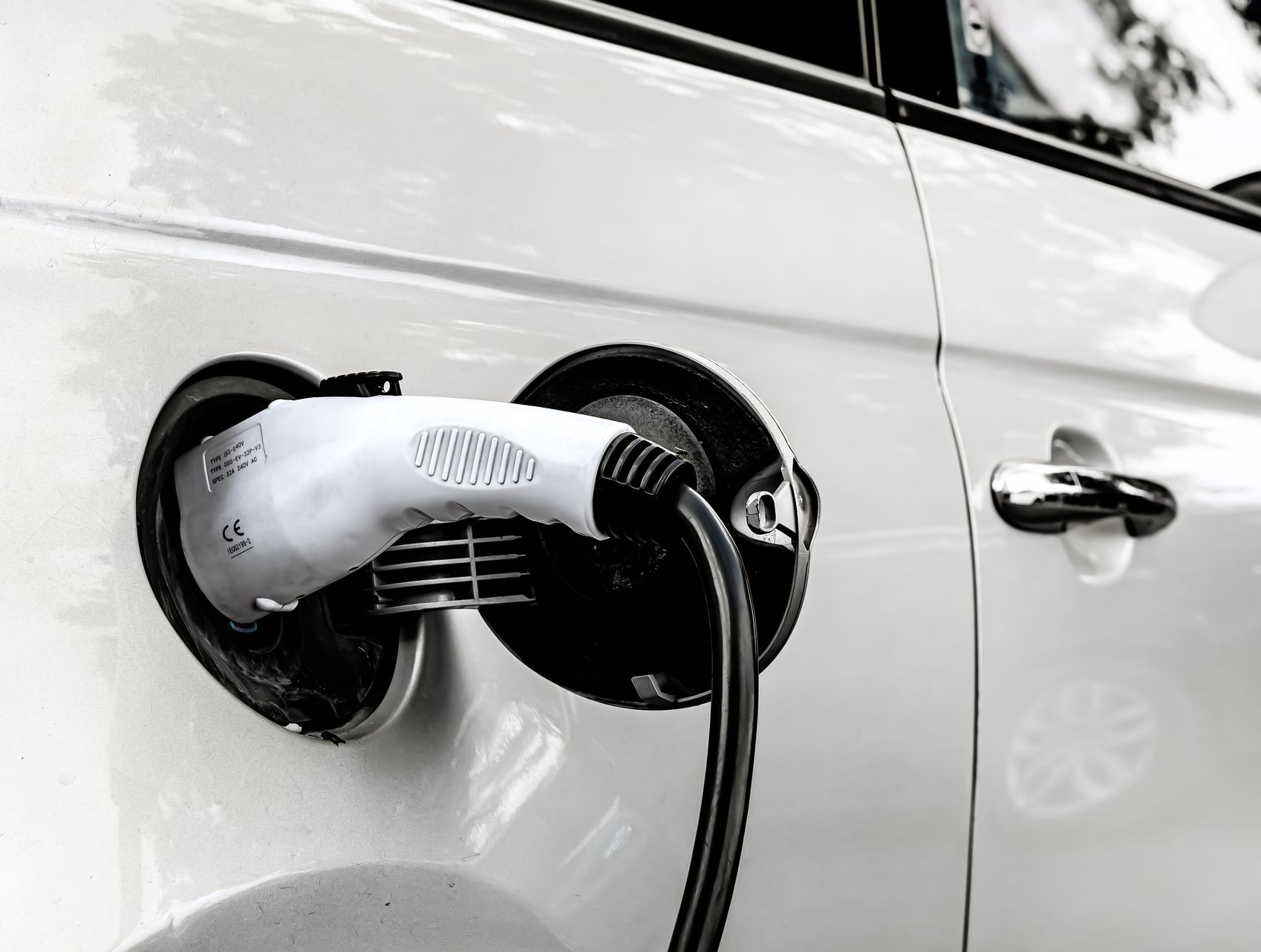 Une voiture électrique blanche en train d'être rechargée.