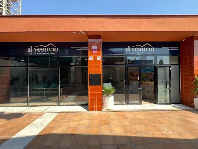 Exterior del restaurante “Il Vesuvio”, un edificio moderno con grandes ventanales y fachada naranja.