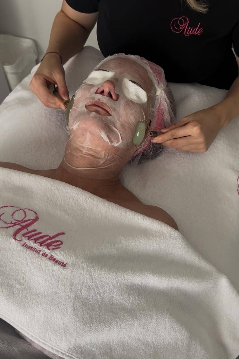 Personne recevant un soin du visage avec masque et pierres de jade dans un spa.