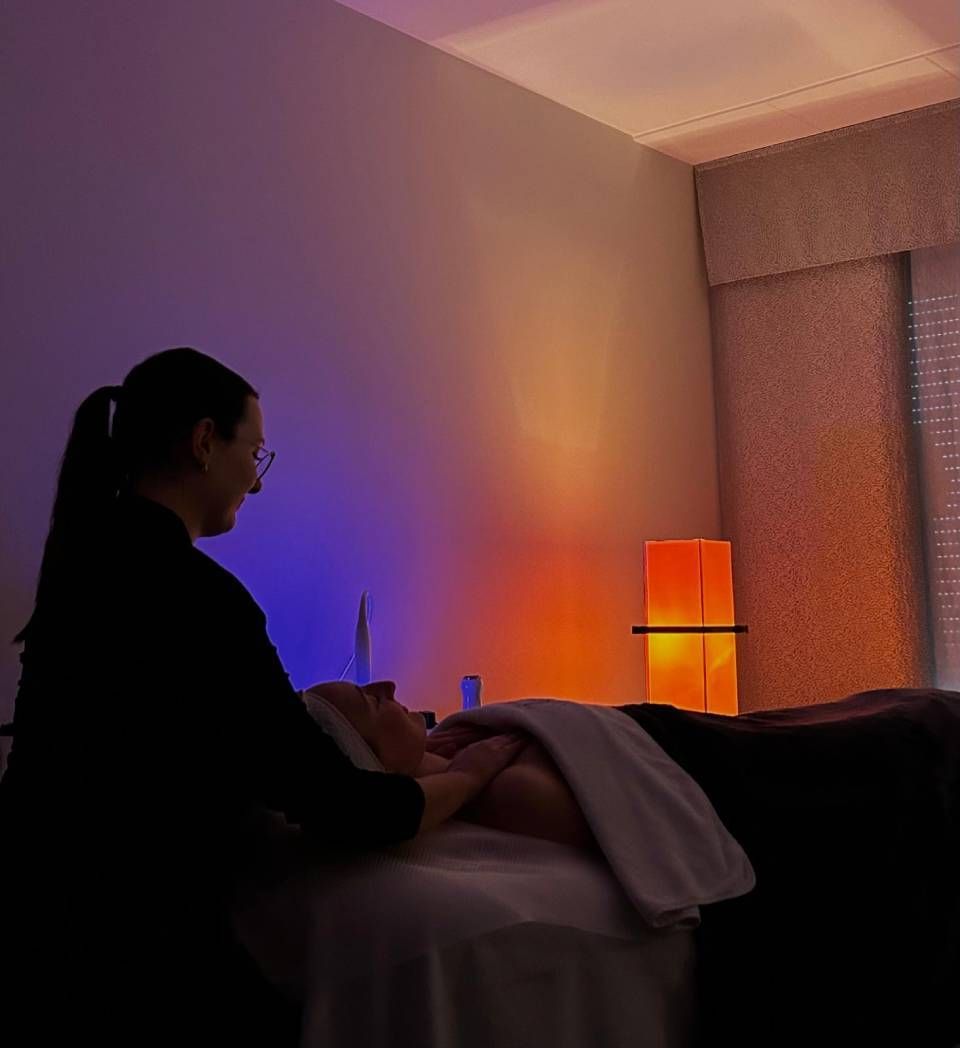 Femme prodiguant un massage facial. Lumière tamisée, ambiance apaisante.