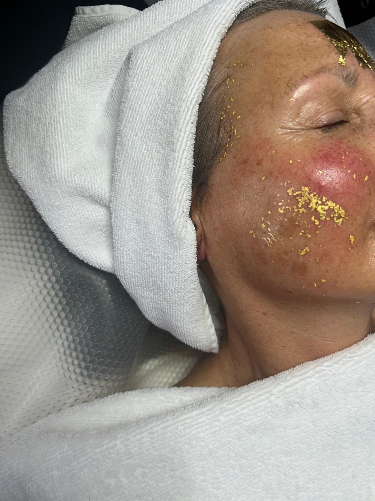 Une personne recevant un massage facial allongée sur une table de soin dans un spa.