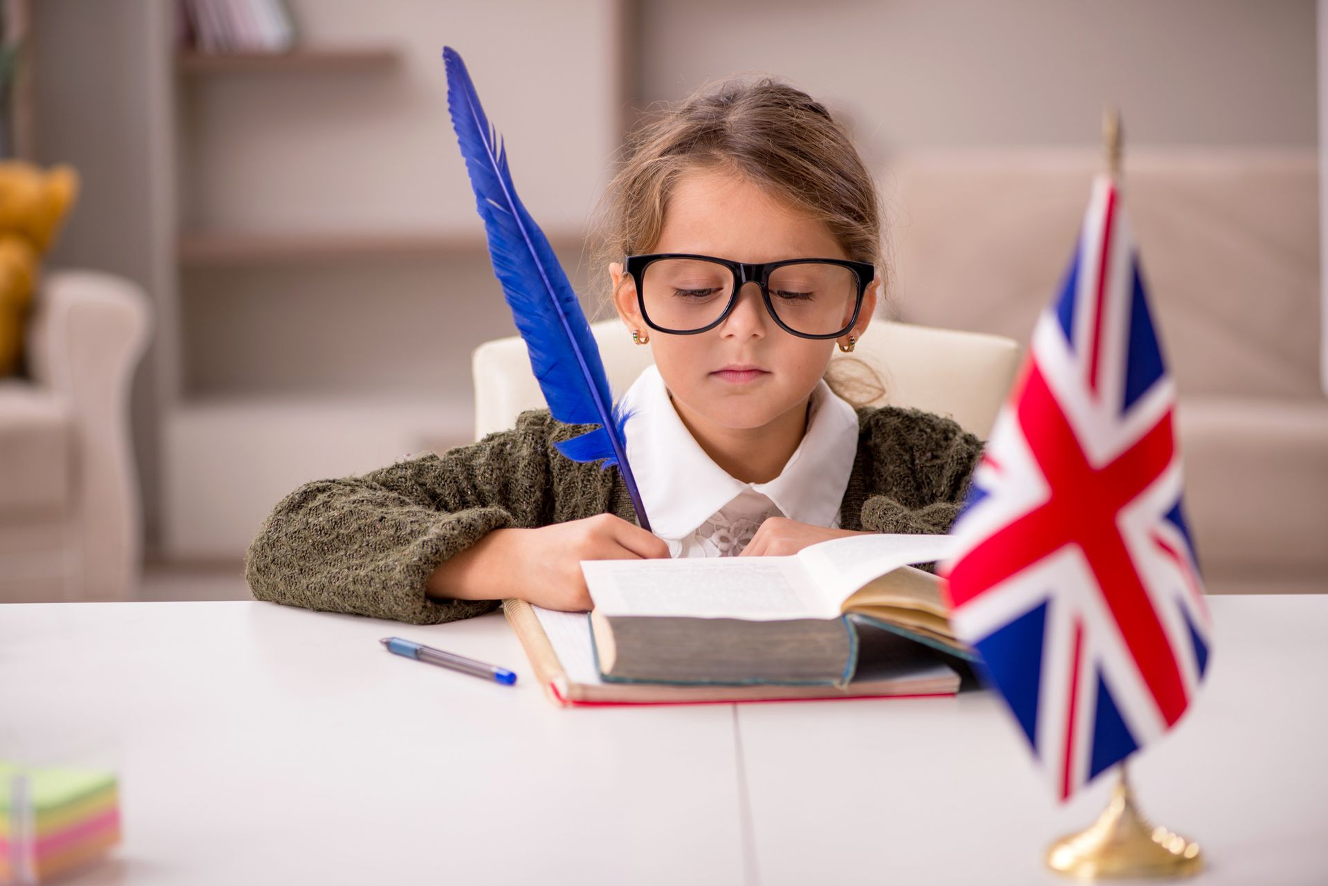 Una niña está sentada en una mesa leyendo un libro.