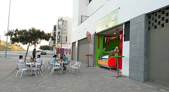 Un grupo de personas están sentadas en mesas afuera de una heladería.