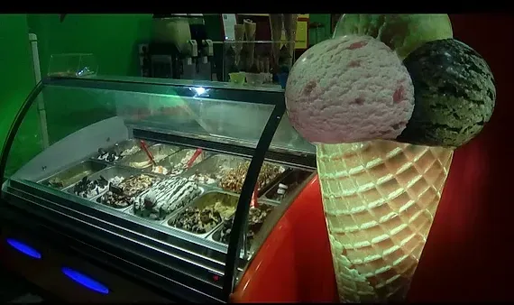 Una vitrina llena de conos y bolas de helado.