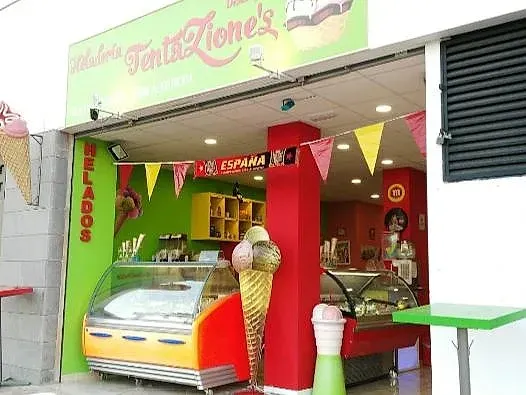 Una heladería colorida con un gran cono de helado frente a ella.