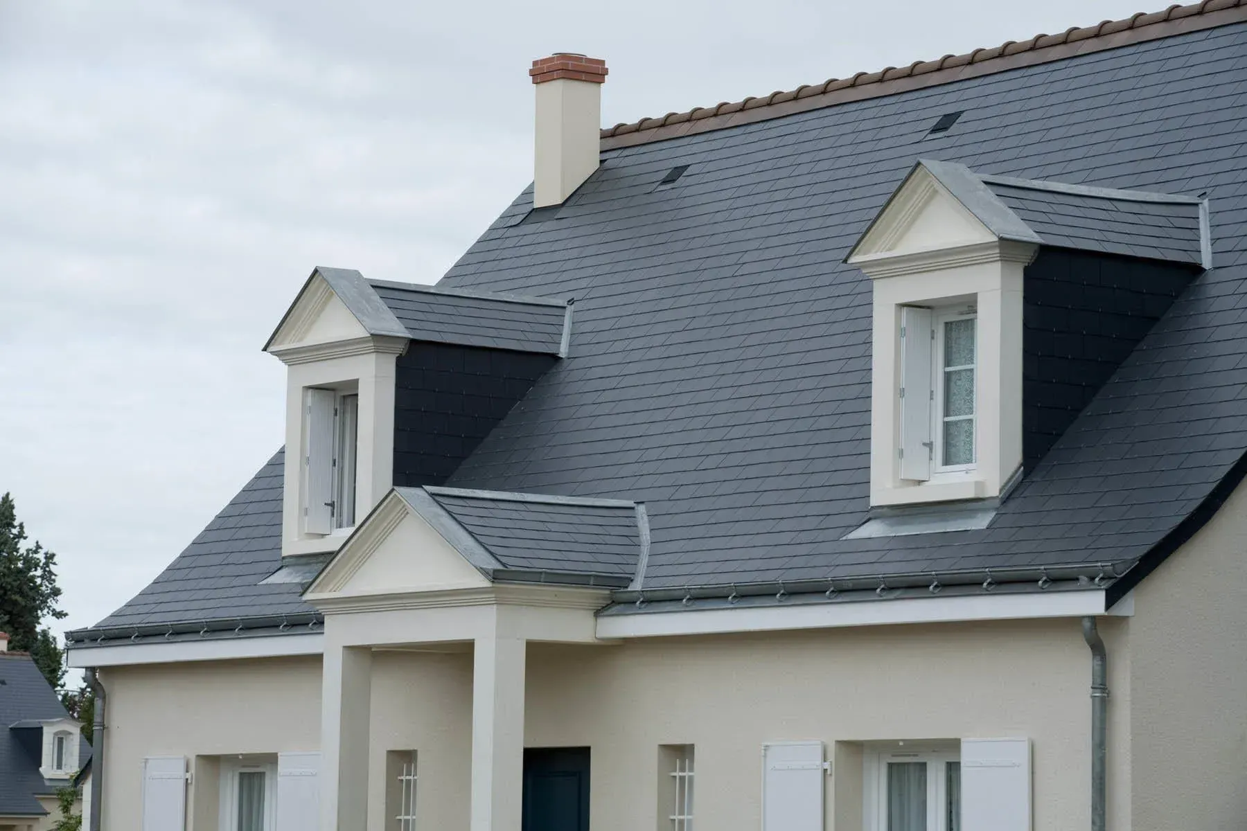 Toiture en ardoise rénovée sur maison traditionnelle, avec lucarnes, zinguerie et finitions de couverture de qualité.