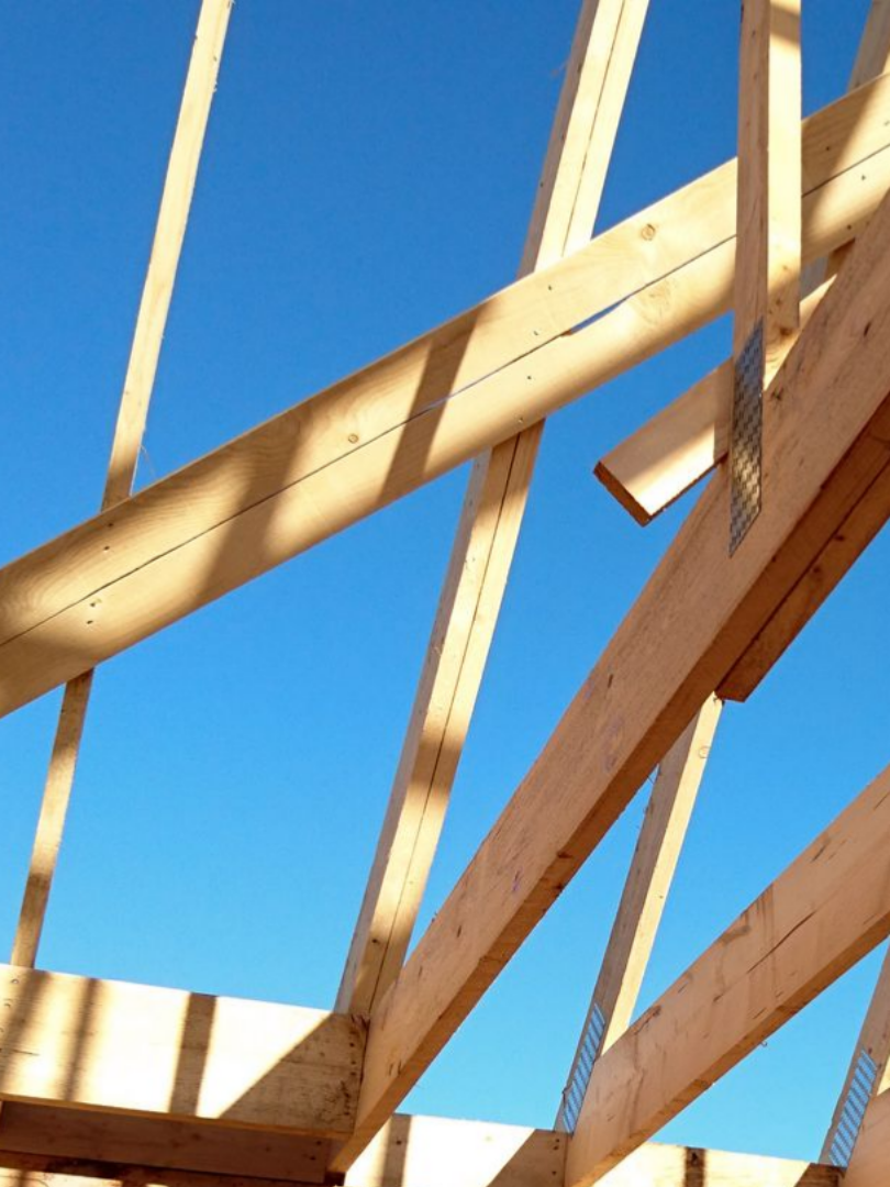 Charpente de toit en bois se détachant sur un ciel d'un bleu éclatant.