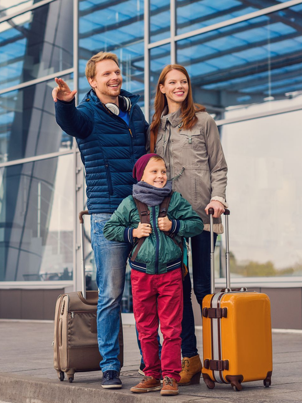 Famille avec bagages à l'extérieur de l'aéroport ; l'homme montre du doigt.