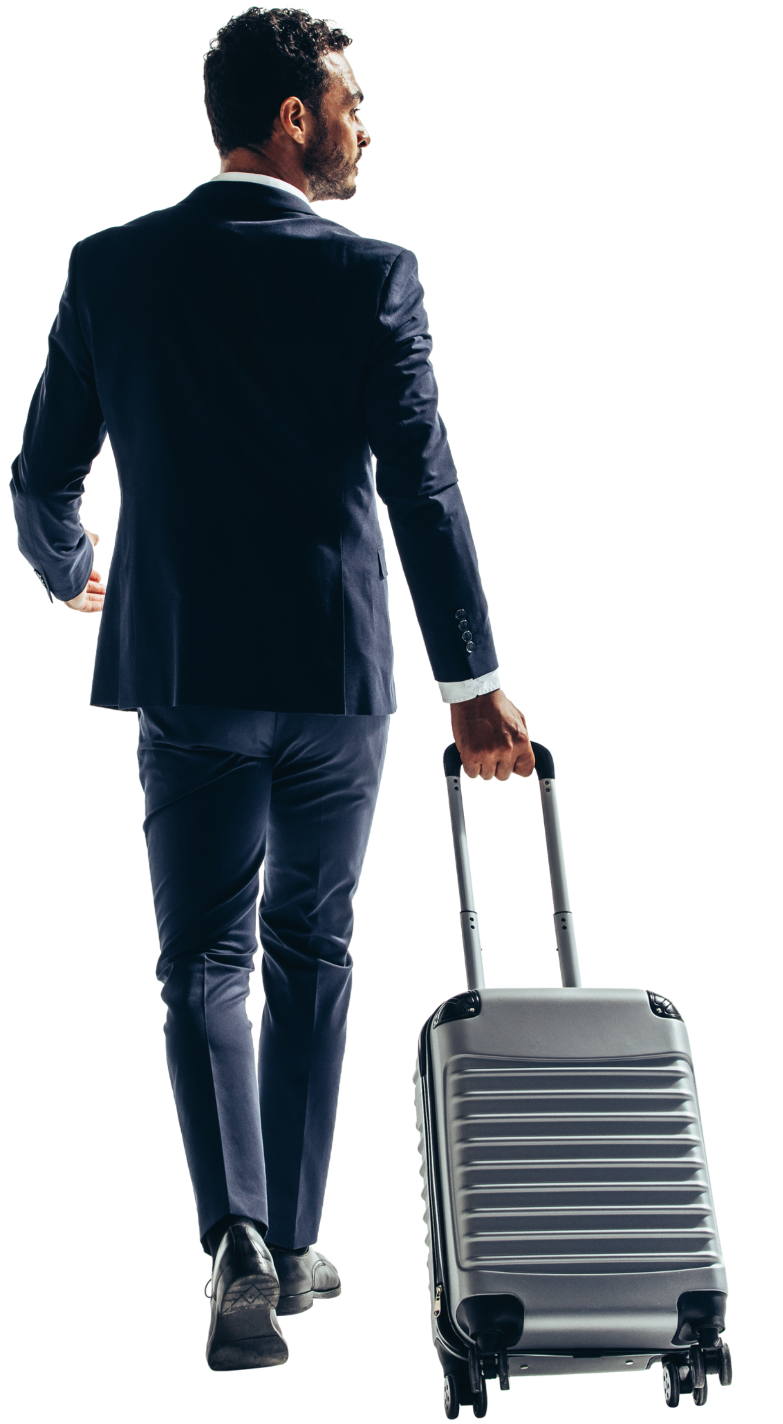 Un homme en costume marche, tire une valise.