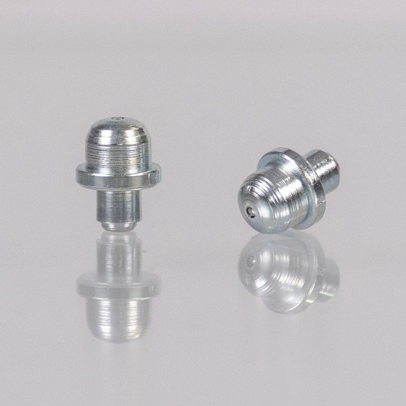 Zwei Schmiernippel aus Metall, Nahaufnahme, auf einer reflektierenden weißen Oberfläche.